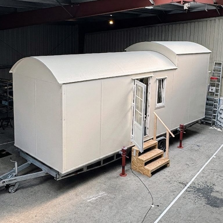 Einfarbiges Tiny House mit Runddach in Produktionshalle.