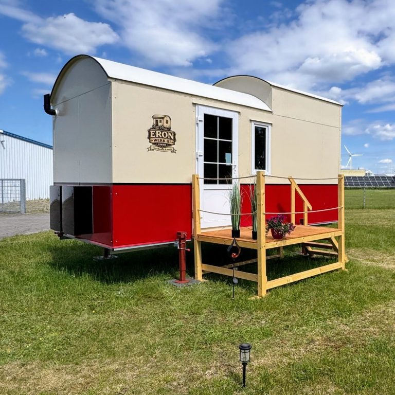 Tiny House mit Runddach und rotem Strich mit Terrasse.